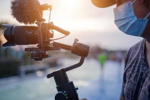 blogger nieuw normaal draagmasker gebruik gimbal-stabilisator en camera-video-opnamen buitenshuis. dit is de levensstijl van de maker van de inhoud tijdens de uitbraak van het coronavirus of covid 19. foto