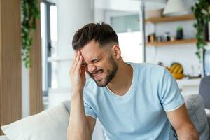 detailopname van jong Mens lijden van hoofdpijn Bij huis, aanraken zijn tempels, kopiëren ruimte, wazig achtergrond. migraine, hoofdpijn, spanning, spanning probleem, kater concept foto