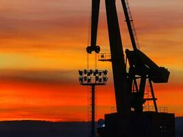 silhouet van de haven kraan Bij verbazingwekkend rood zonsondergang foto