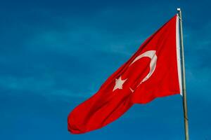 Turks vlag. golvend vlag van turkiye Aan blauw lucht achtergrond foto