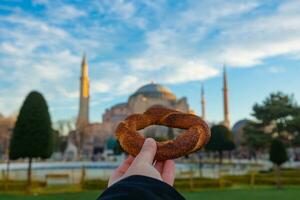 simit of Turks bagel Aan de hand- van een Mens en hagia sophia Aan de achtergrond foto