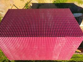 een huis met een rood dak gemaakt van gegolfd metaal bladen. dak van gegolfd metaal profiel. metaal tegels. foto