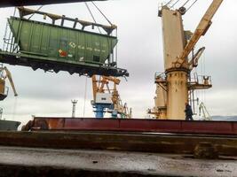 in beweging vracht spoorweg auto in de haven door een haven kraan. lading hijs- activiteiten. industrieel haven foto