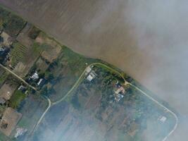 top visie van de klein dorp. rook van de brandend van rietje is verspreiding over- de dorp foto