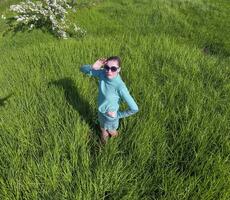 jong meisje in een licht groen jurk Aan de gazon met groen gras. visie van een Mens van bovenstaand van een hoogte. foto