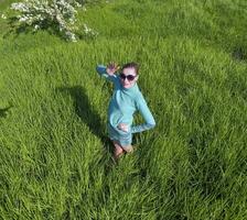 jong meisje in een licht groen jurk Aan de gazon met groen gras. visie van een Mens van bovenstaand van een hoogte. foto