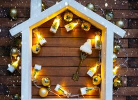 sleutel naar huis met een sleutelhanger klein huis Aan houten achtergrond met Kerstmis decor indeling. geschenk voor nieuw jaar, kerstmis. gebouw, projecteren, in beweging naar nieuw huis, hypotheek, huur en aankoop echt landgoed foto