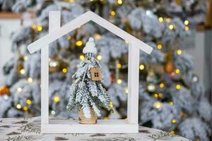 sleutel Aan Kerstmis boom en klein huis Aan knus huis met Kerstmis decor Aan tafel van feestelijk wit keuken. geschenk voor nieuw jaar. verzekering, in beweging naar nieuw huis, hypotheek, huur en echt landgoed foto