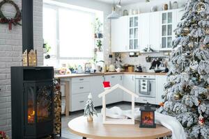 Kerstmis decor in wit keuken met brandend fornuis haard, feestelijk troep, dorp interieur met een besneeuwd Kerstmis boom. nieuw jaar, Kerstmis stemming, knus huis. foto