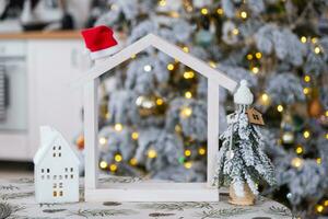 sleutel Aan Kerstmis boom en klein huis Aan knus huis met Kerstmis decor Aan tafel van feestelijk wit keuken. geschenk voor nieuw jaar. verzekering, in beweging naar nieuw huis, hypotheek, huur en aankoop echt landgoed foto