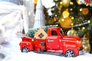 rood retro auto met een Kerstmis boom siert met de huis sleutel in de oppakken vrachtauto voor kerstmis. buying een huis, in beweging, hypotheek, lening, echt landgoed, feestelijk stemming, nieuw jaar foto