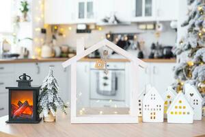 sleutel en klein huis van een klein grootte Aan knus huis met Kerstmis decor Aan tafel van feestelijk wit keuken. geschenk voor nieuw jaar. verzekering, in beweging naar nieuw huis, hypotheek, huur en aankoop echt landgoed foto