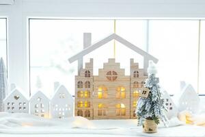 sleutel Aan Kerstmis boom en klein huis Aan knus huis met Kerstmis decor Aan tafel van feestelijk wit keuken. geschenk voor nieuw jaar. verzekering, in beweging naar nieuw huis, hypotheek, huur en echt landgoed foto