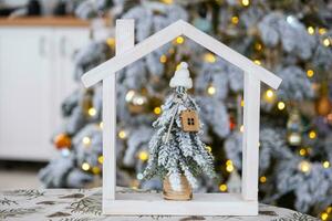 sleutel Aan Kerstmis boom en klein huis Aan knus huis met Kerstmis decor Aan tafel van feestelijk wit keuken. geschenk voor nieuw jaar. verzekering, in beweging naar nieuw huis, hypotheek, huur en echt landgoed foto