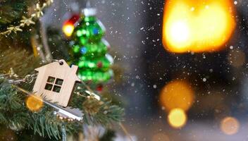 sleutel van het huis met een sleutelhanger hangt aan de kerstboom. een cadeau voor het nieuwe jaar, kerstmis. bouwen, ontwerp, project, verhuizen naar nieuw huis, hypotheek, huur en aankoop onroerend goed. kopieer ruimte foto