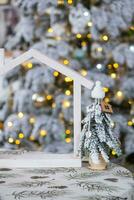 sleutel Aan Kerstmis boom en klein huis Aan knus huis met Kerstmis decor Aan tafel van feestelijk wit keuken. geschenk voor nieuw jaar. verzekering, in beweging naar nieuw huis, hypotheek, huur en echt landgoed foto