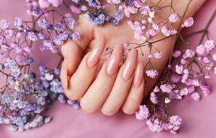 vrouw handen met roze nagel ontwerp houden gypsophila bloemen. foto