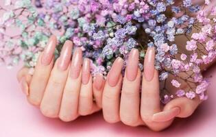 vrouw handen met roze nagel ontwerp houden gypsophila bloemen. foto