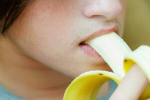 portret van een tiener- jongen aan het eten een banaan. foto van een jongens mond en lippen met een banaan. vers fruit. gezond voedingsmiddelen voor kinderen