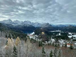alpine idylle met alpen, met sneeuw bedekt bossen en bergen en hohenschwangau kasteel foto