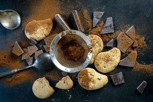 koekjes en stukken van chocola besprenkeld met cacao poeder Aan een zwart achtergrond foto