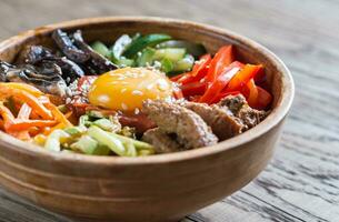 kom van Bibimbap Aan de houten tafel foto