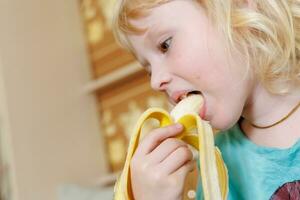 portret van een weinig meisje aan het eten een banaan. de concept van gezond voedsel. een vers snel tussendoortje foto