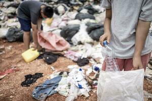 arm kinderen Aan de vuilnis dump en selecteren plastic verspilling naar verkopen, kinderen niet in school, armoede. foto