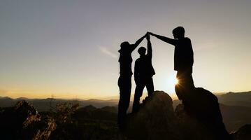 silhouet van samenspel van drie wandelaar helpen elk andere Aan top van berg beklimming team. samenspel vriendschap wandelen helpen elk andere vertrouwen bijstand silhouet in bergen, zonsopkomst. foto