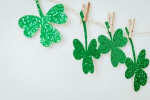 gelukkig st. patricks dag. groen schitteren klavers decoratie. eigengemaakt slinger van touw en Klaver bladeren Aan wasknijpers foto