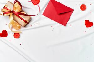 romantisch concept. valentijnsdag dag achtergrond. rood envelop, geschenk doos en harten Aan wit zijde vel foto