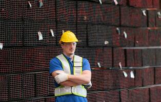 portret van een bouw arbeider staand met armen gekruiste in voorkant van staal materiaal muur foto