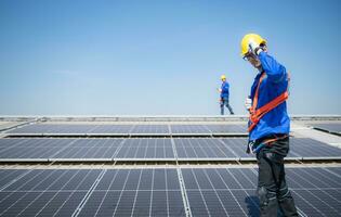 beide van technici is installeren zonne- panelen Aan de dak van de magazijn naar verandering zonne- energie in elektrisch energie voor gebruik in fabrieken. foto