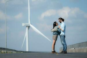 Aan de weg, een jong paar stelt voor naar elk ander, met wind turbines in de achtergrond. foto