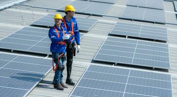 beide van technici is installeren zonne- panelen Aan de dak van de magazijn naar verandering zonne- energie in elektrisch energie voor gebruik in fabrieken. foto