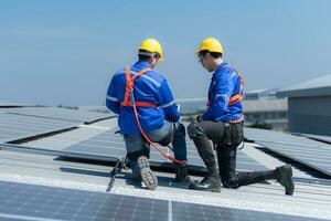 beide van technici is installeren zonne- panelen Aan de dak van de magazijn naar verandering zonne- energie in elektrisch energie voor gebruik in fabrieken. foto