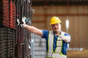 portret van een bouw arbeider staand met duimen omhoog in voorkant van staal materiaal muur foto