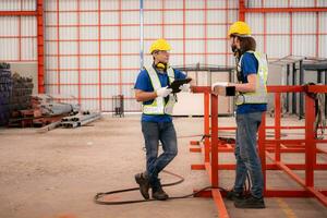 portret van twee arbeiders gebruik makend van digitaal tablet staan in voorkant van de rood staal structuur foto