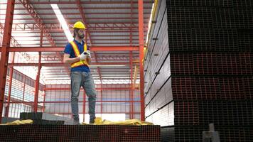 magazijn arbeider in moeilijk hoeden en helmen, inspecteren en tellen staal in de magazijn. foto