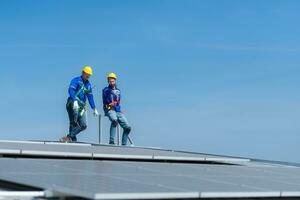 een jong technicus intern werken Aan zonne- panelen is angst van hoogten met senior ingenieurs wie zijn altijd helpen uit foto