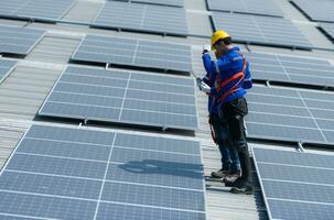 beide van technici is installeren zonne- panelen Aan de dak van de magazijn naar verandering zonne- energie in elektrisch energie voor gebruik in fabrieken. foto