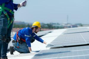 beide van technici is installeren zonne- panelen Aan de dak van de magazijn naar verandering zonne- energie in elektrisch energie voor gebruik in fabrieken. foto