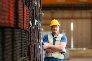 portret van een bouw arbeider staand met armen gekruiste in voorkant van staal materiaal muur foto