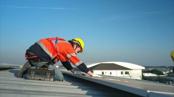 beide van technici is installeren zonne- panelen Aan de dak van de magazijn naar verandering zonne- energie in elektrisch energie voor gebruik in fabrieken. foto