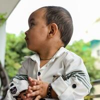 baby jongen Bij huis balkon. helder portret van gelukkig kind zittend Aan de tafel. weinig 1 jaar oud jongen gedurende de dag licht Bij huis balkon. foto