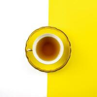 geel thee kop Aan een wit en geel achtergrond foto