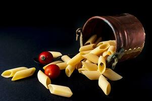vers penne rigeren macaroni pasta en kers tomaten in een koper peul foto
