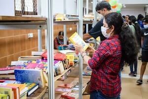 Delhi, Indië, september 09 2023 - divers leeftijd groep mensen lezing verscheidenheid van boeken Aan plank binnen een boekenstalletje Bij Delhi Internationale boek eerlijk, selectie van boeken Aan Scherm in jaar- boek eerlijk foto