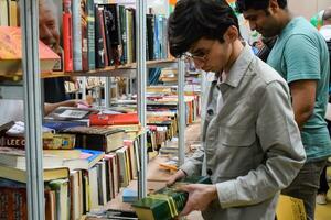 Delhi, Indië, september 09 2023 - divers leeftijd groep mensen lezing verscheidenheid van boeken Aan plank binnen een boekenstalletje Bij Delhi Internationale boek eerlijk, selectie van boeken Aan Scherm in jaar- boek eerlijk foto