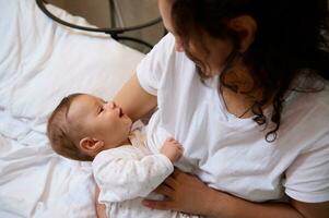 authentiek gelukkig vrouw moeder glimlachen borstvoeding geeft en knuffelen haar pasgeboren baby. mensen. moederschap vertrekken levensstijl. foto